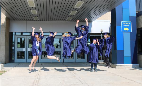 graduates jumping in front of the school