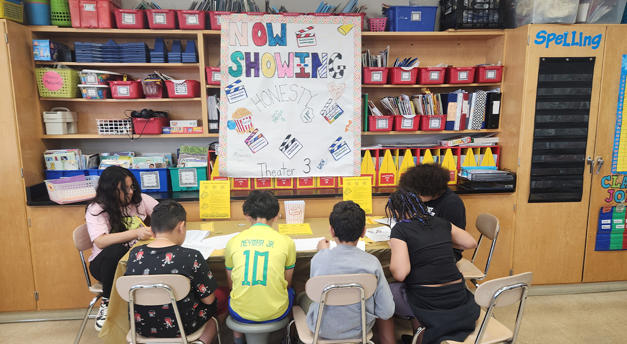 Fourth grade students reading at table.