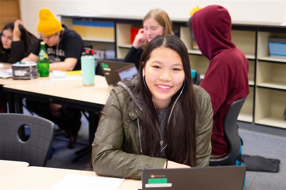 Student smiling while working on Chromebook 