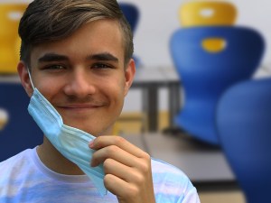 boy putting on a mask in a classroom