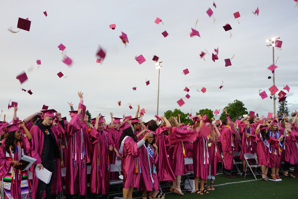 students dressed in cap and gowns for graduation throwing their hats in the air