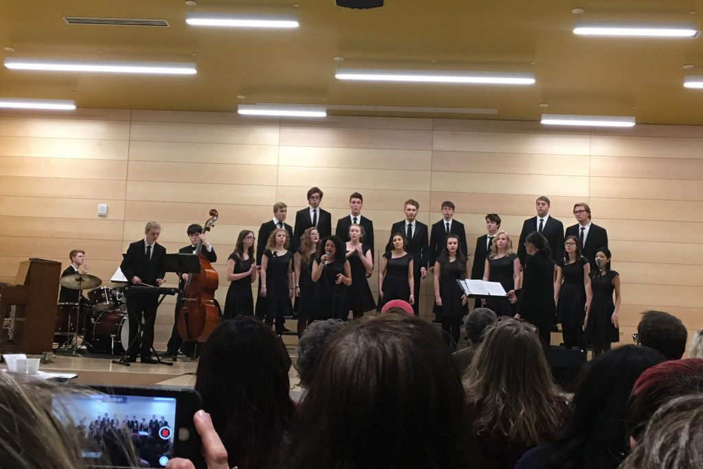 a group of students singing, accompanied by students playing instruments