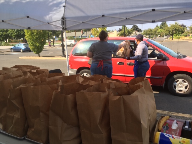 Handing bags of food through a car window.