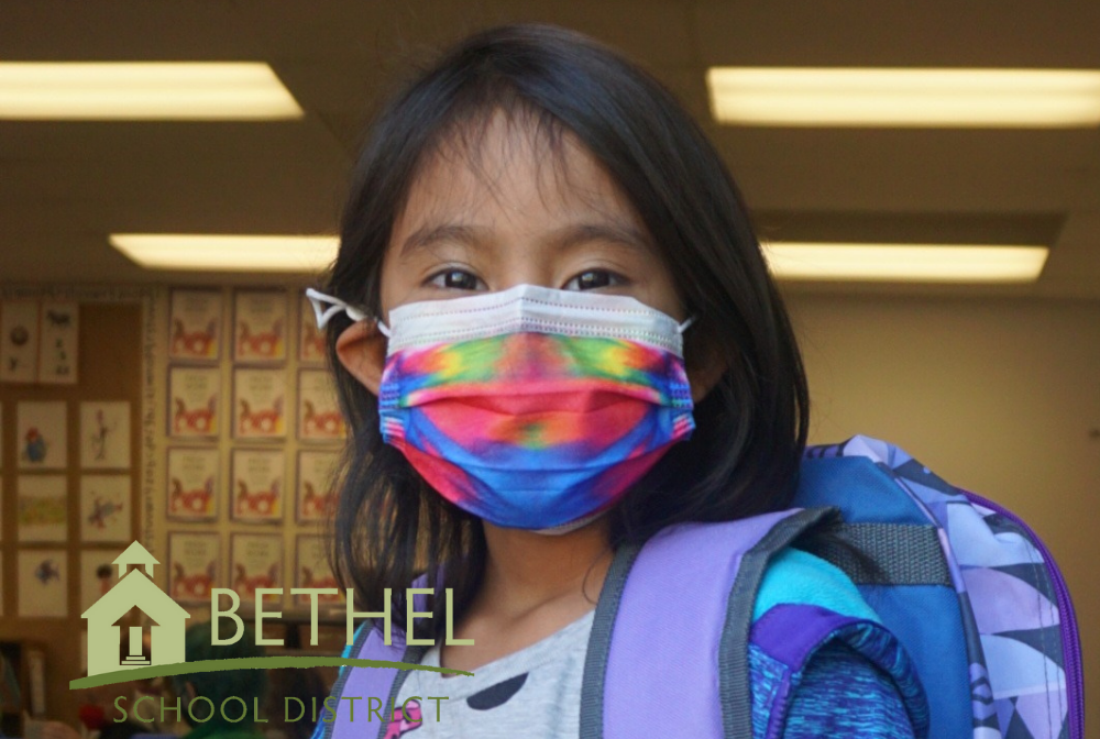 masked student wearing backpack looking at camera