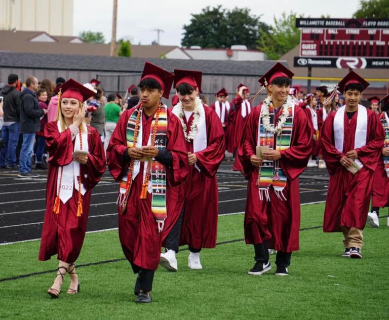 students in graduation cap and gown walking the field at WHS stadium