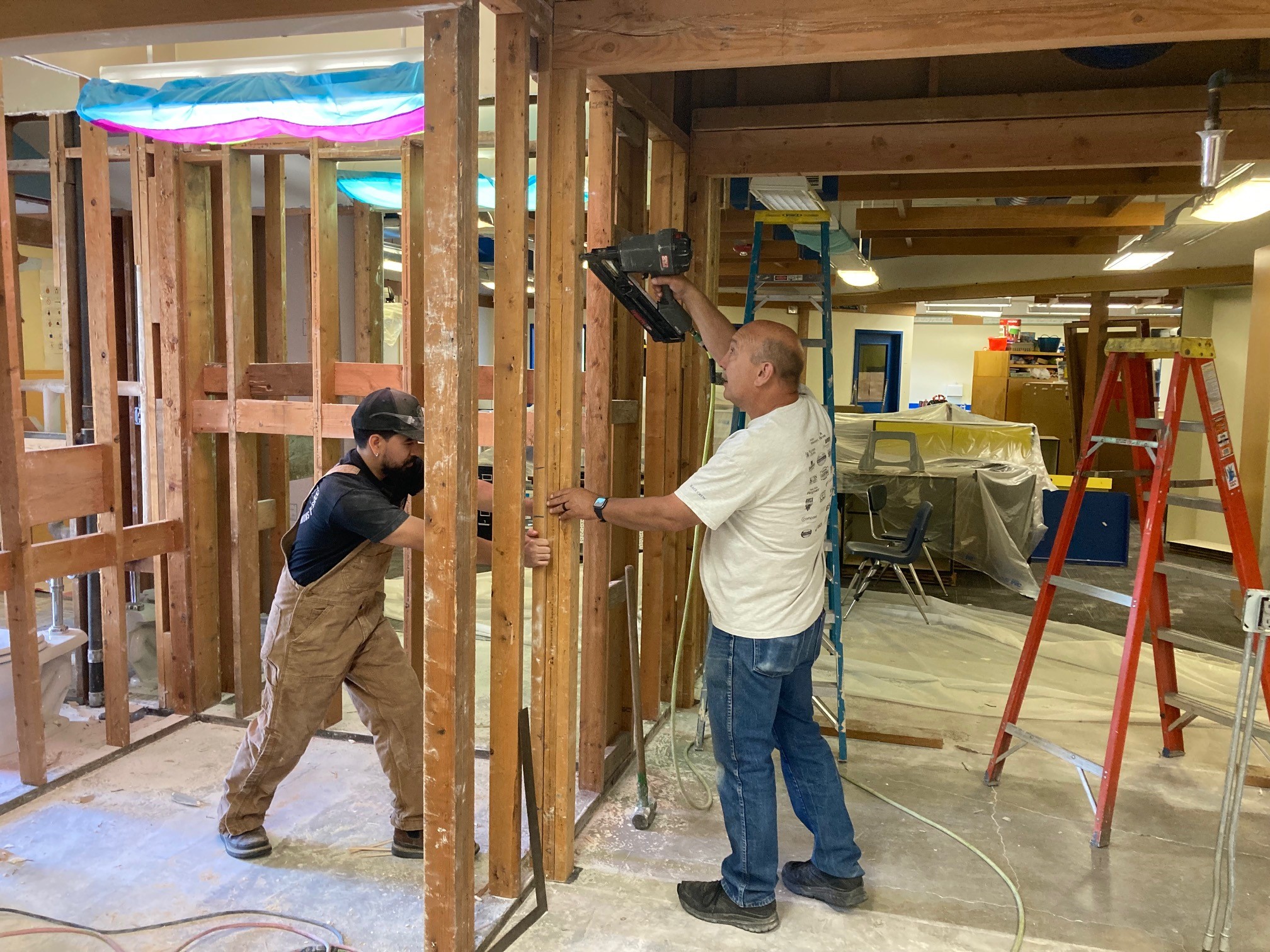 Two men nailing walls in place to build a classroom