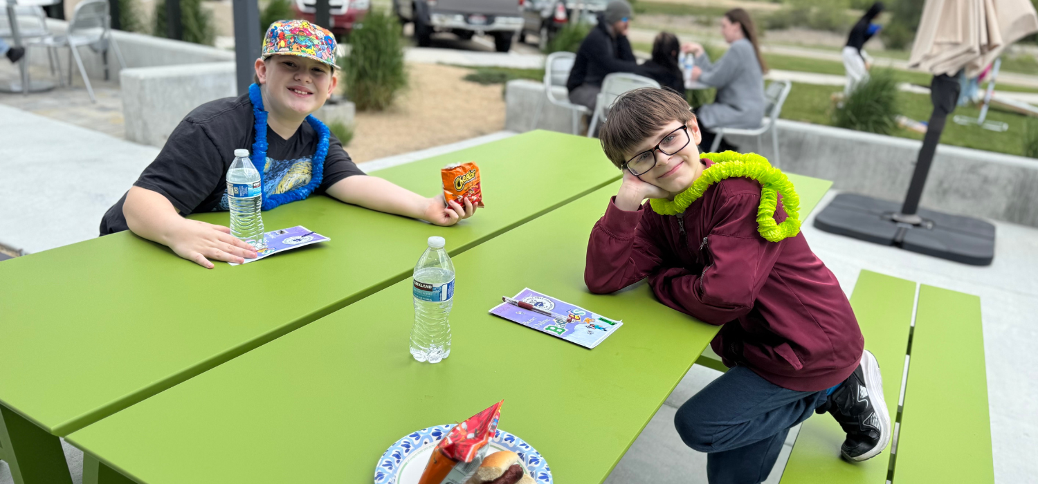 Two elementary students sign each other's yearbooks at the BBQ.