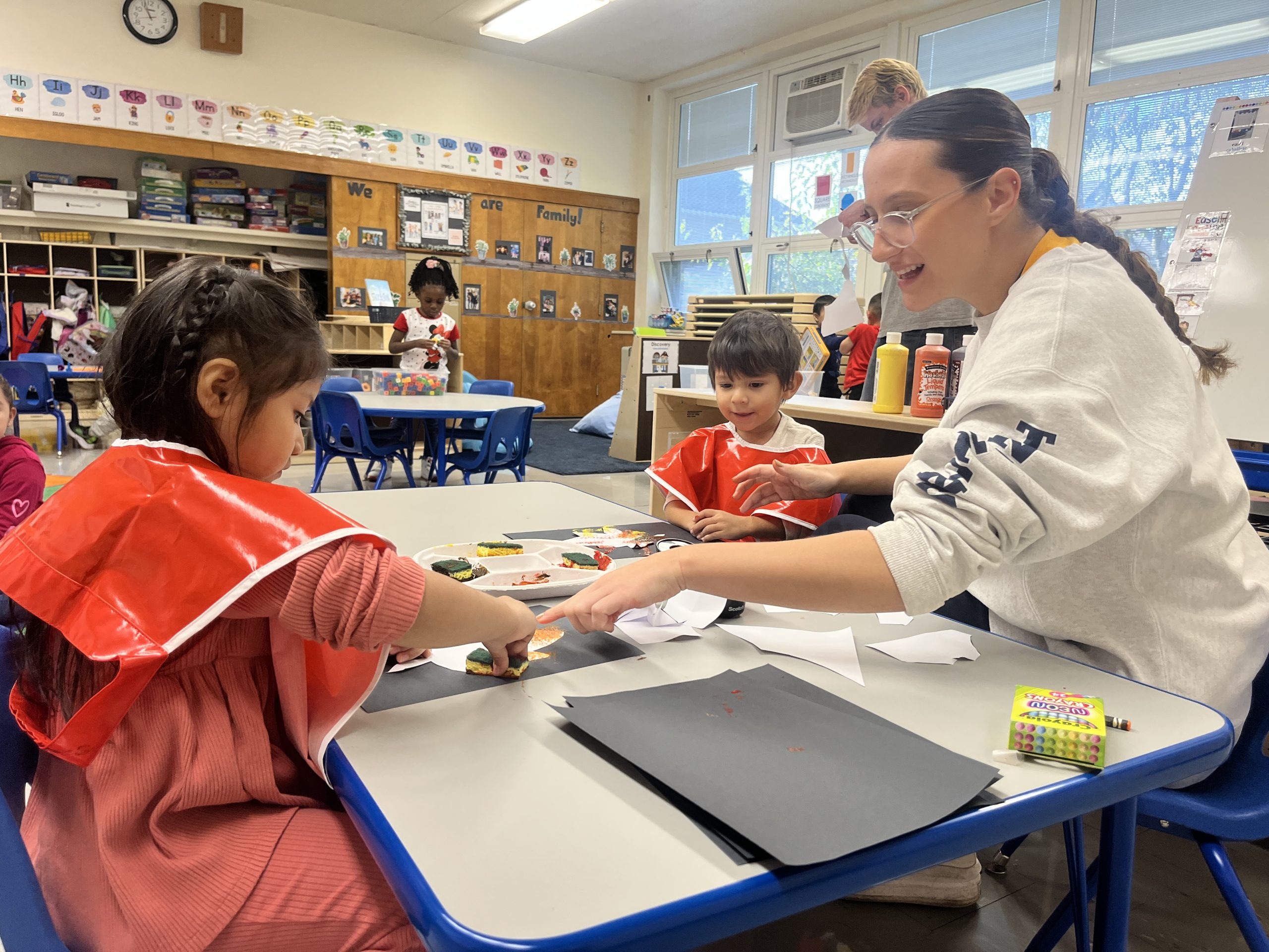 Jordan Todaro A teacher shows a student how to do an activity in a pre-kindergarten classroom