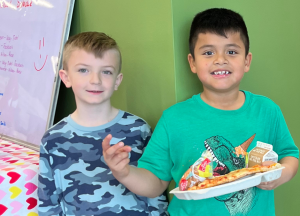 Jonathan Bal, a second grader at Lafayette, with his friend enjoying pizza Friday.