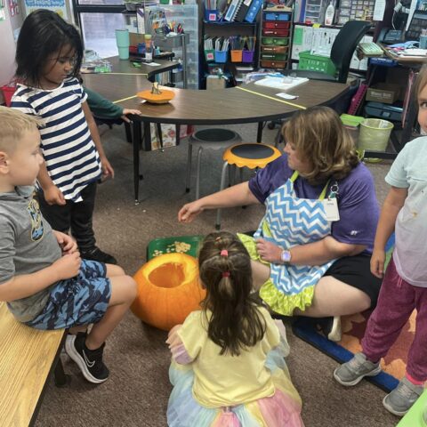 photo of teacher and students carving pumpkins