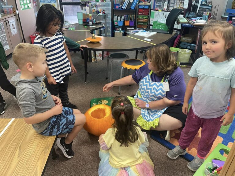 photo of teacher and students carving pumpkins