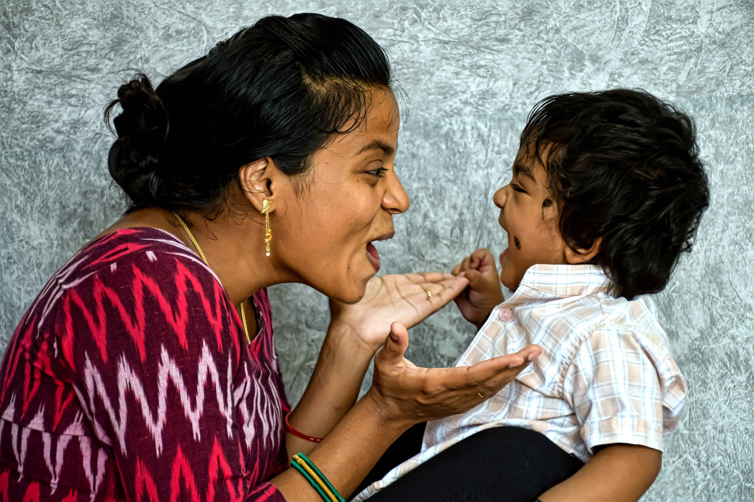 sideview of a mother facing her child holding her hands out