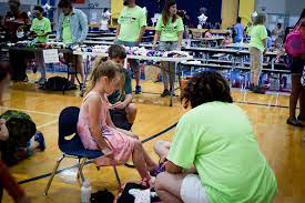 An adult helping a child pick out shoes