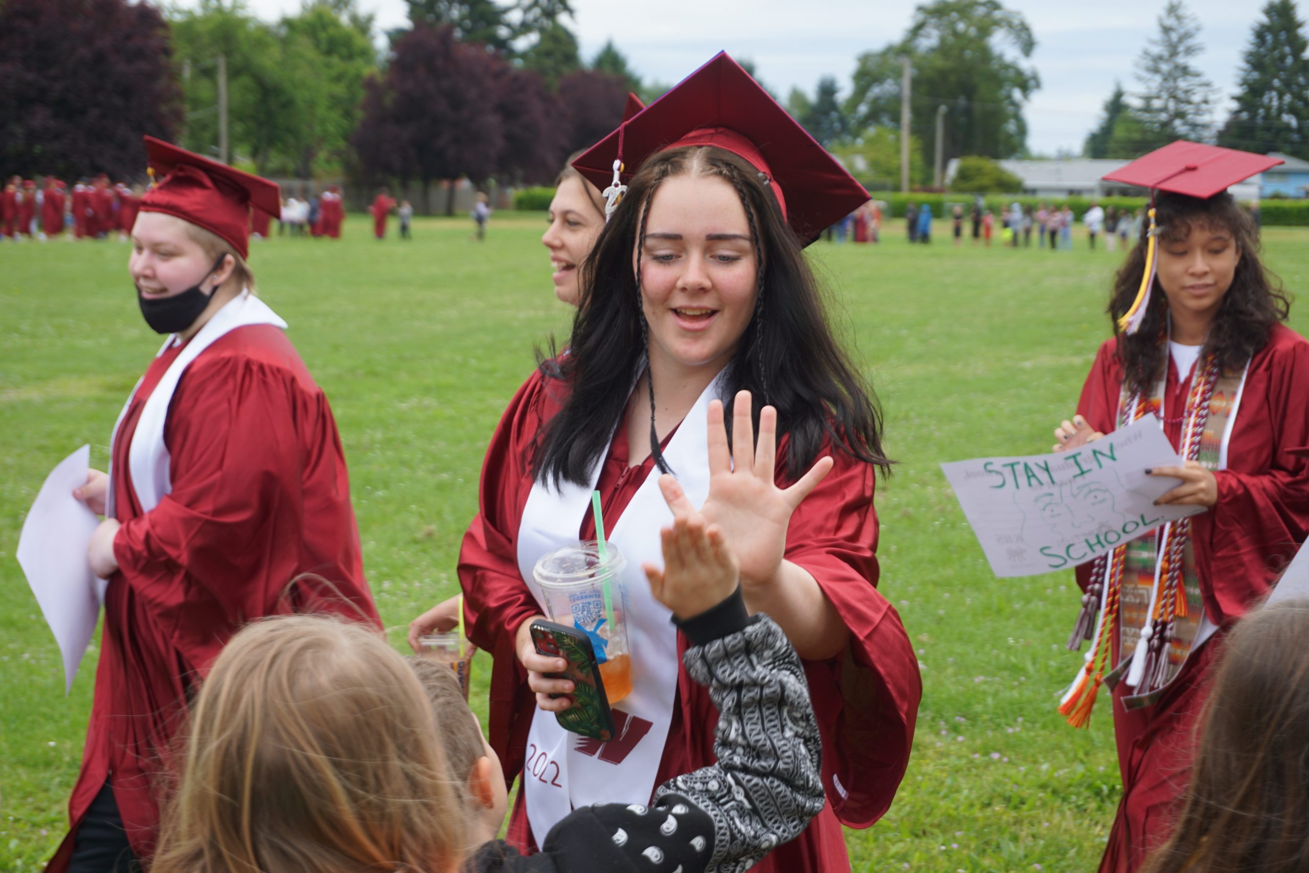 High school student high fiving an elementary school student outside of Irving elementary during the graduation walk.