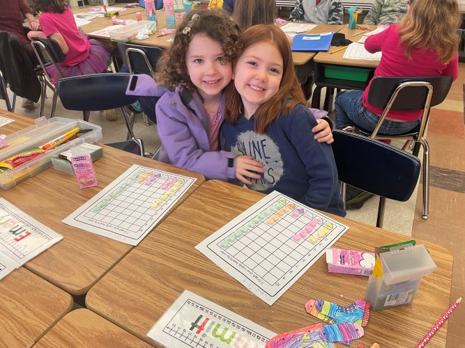 2 students at desk smiling