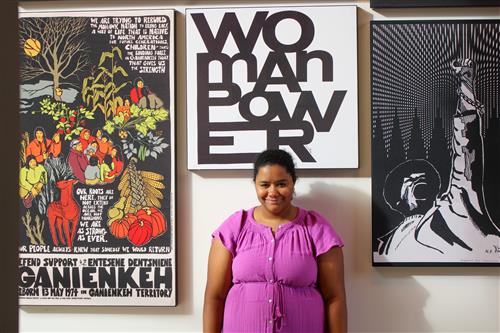  A woman posing in front of artwork in a purple dress 