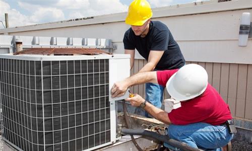 AC students working on air conditioning unit.