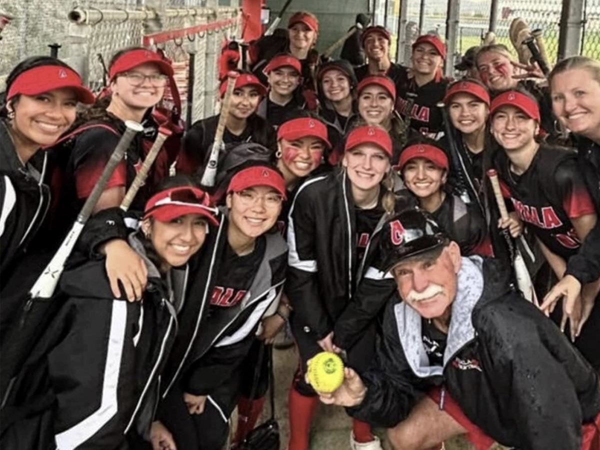 Coach Ameluxen smiling holding a softball with the Ayala softball team
