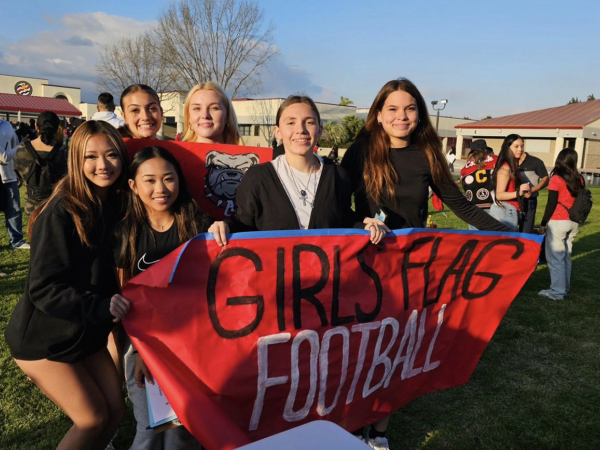 Ayala High flag football team members holding a banner for their team
