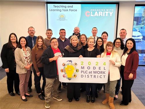 Photo of district administrators and school teachers holding a PLC banner