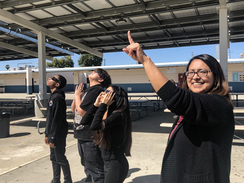 A teacher pointing up at the sky during the solar eclipse