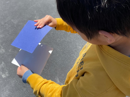 A student using two pieces of paper to observe solar eclipse