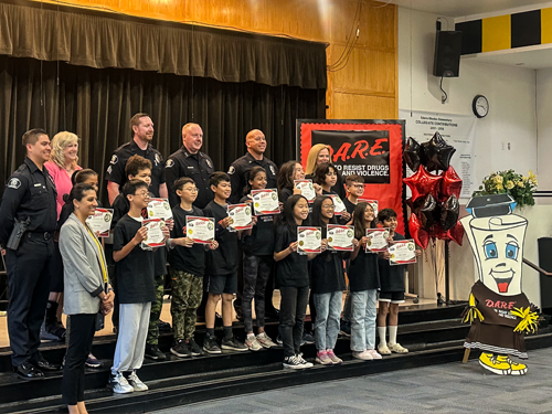 D.A.R.E. graduates posing for a group photo on stage during graduation.