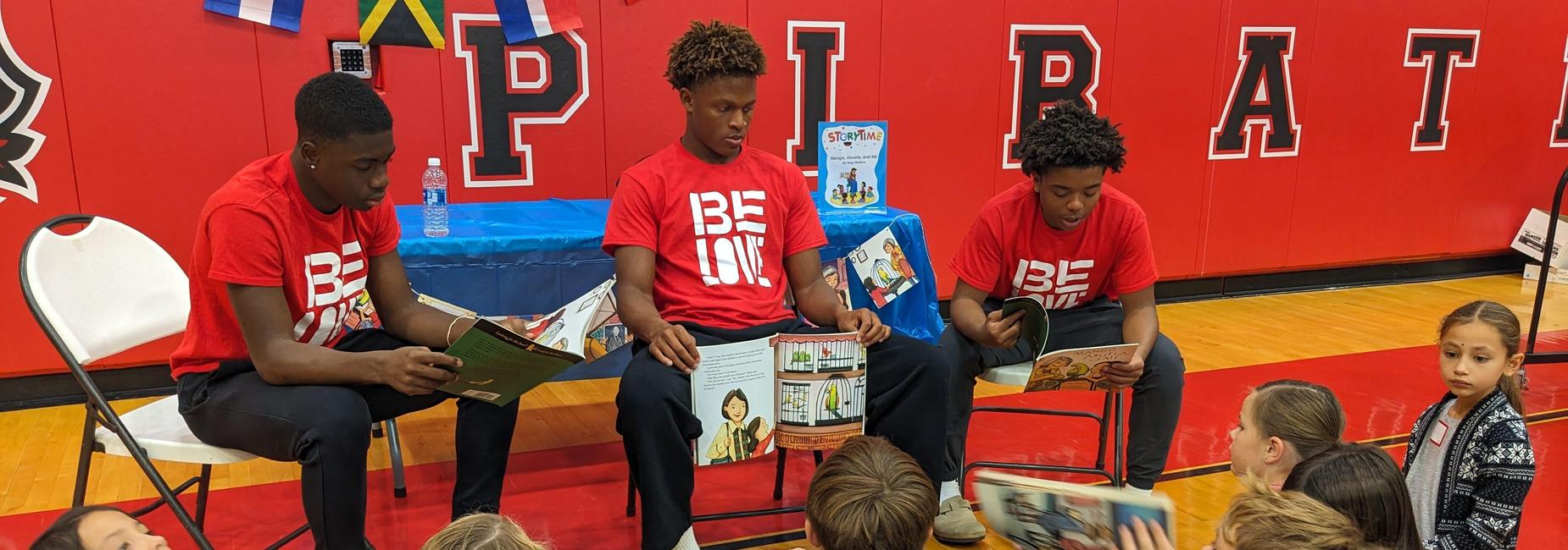 3 male students sitting in chairs reading