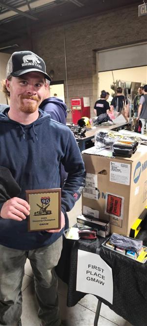Logan Duval stands in front of his prizes with a plaque celebrating his first place win.