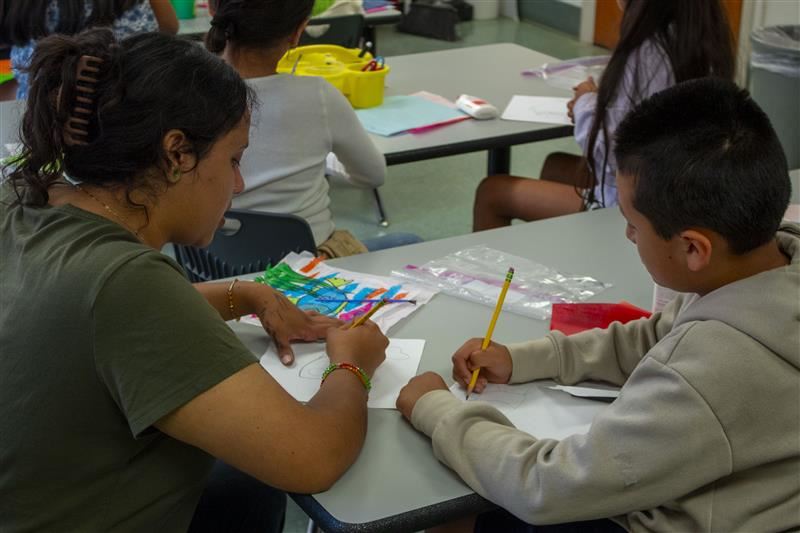  Teacher (left) and student (right) working in the classroom on an art project.