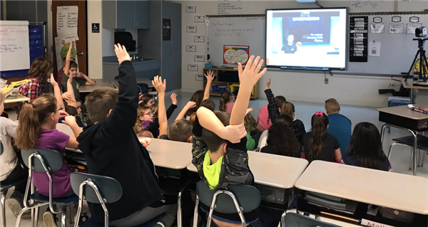 Students raise hands engaging in videoconference.