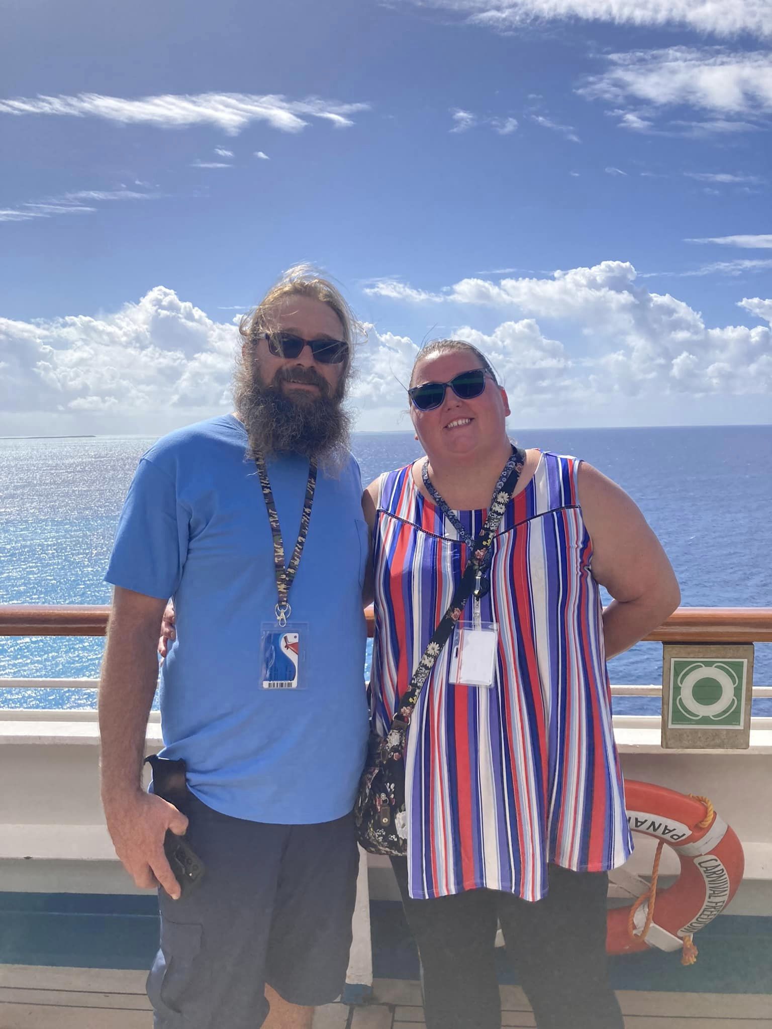 man and woman stading on a cruis ship in front of clouds, sky, and blue water