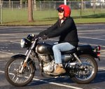 Person on a black motorcycle with a red helmet.