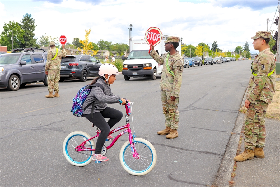 Military officials helping student cross sidewalk