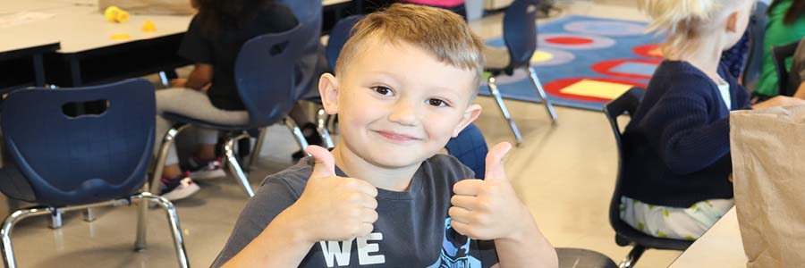Male elementary student smiling and holding up two thumbs up