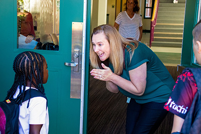 Give 6 Teacher welcoming student into school