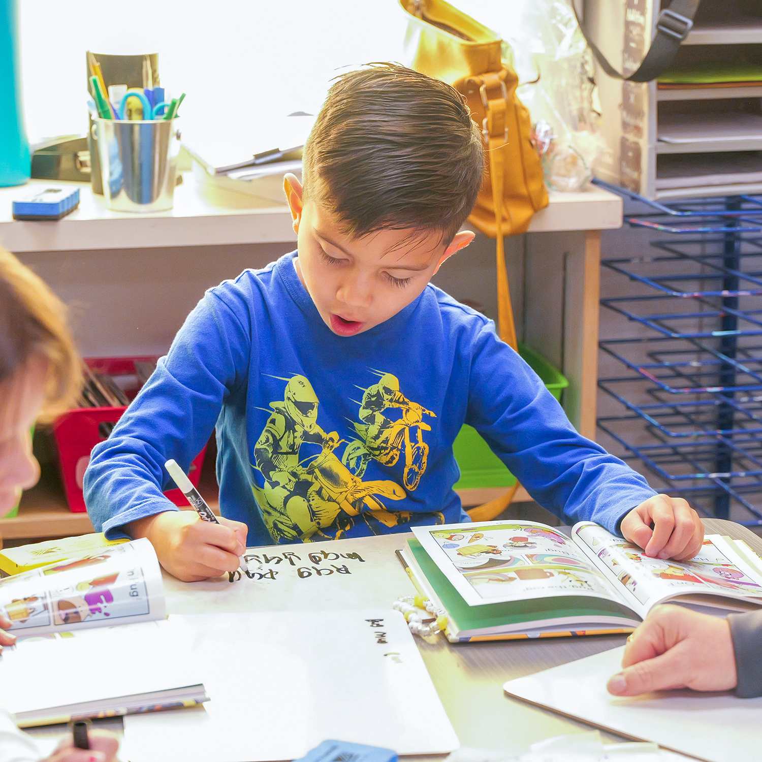 Elementary student practicing writing words out of a book