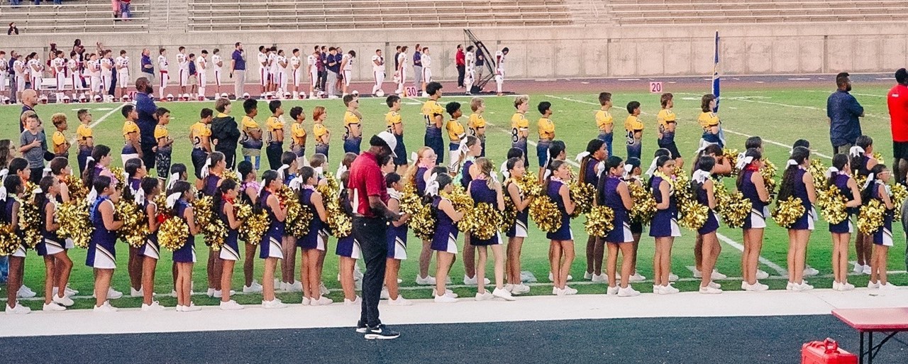 Image of FW football players and cheerleaders pledging allegiance at FW School Feeder Night at Buchanan Stadium.