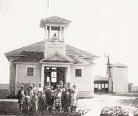 photo of original Fort Washington school house with its first students standing in front of it.