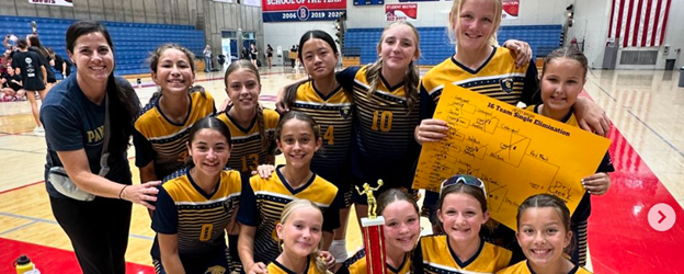 Volleyball Team Posing in uniforms with their first place trophy