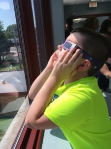 Boy viewing eclipse through window 