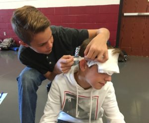 Students learns to bandage another student during First Aid training