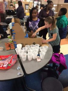 Girls setting up arcade game made of cardboard