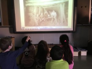 students looking at old photo of miners