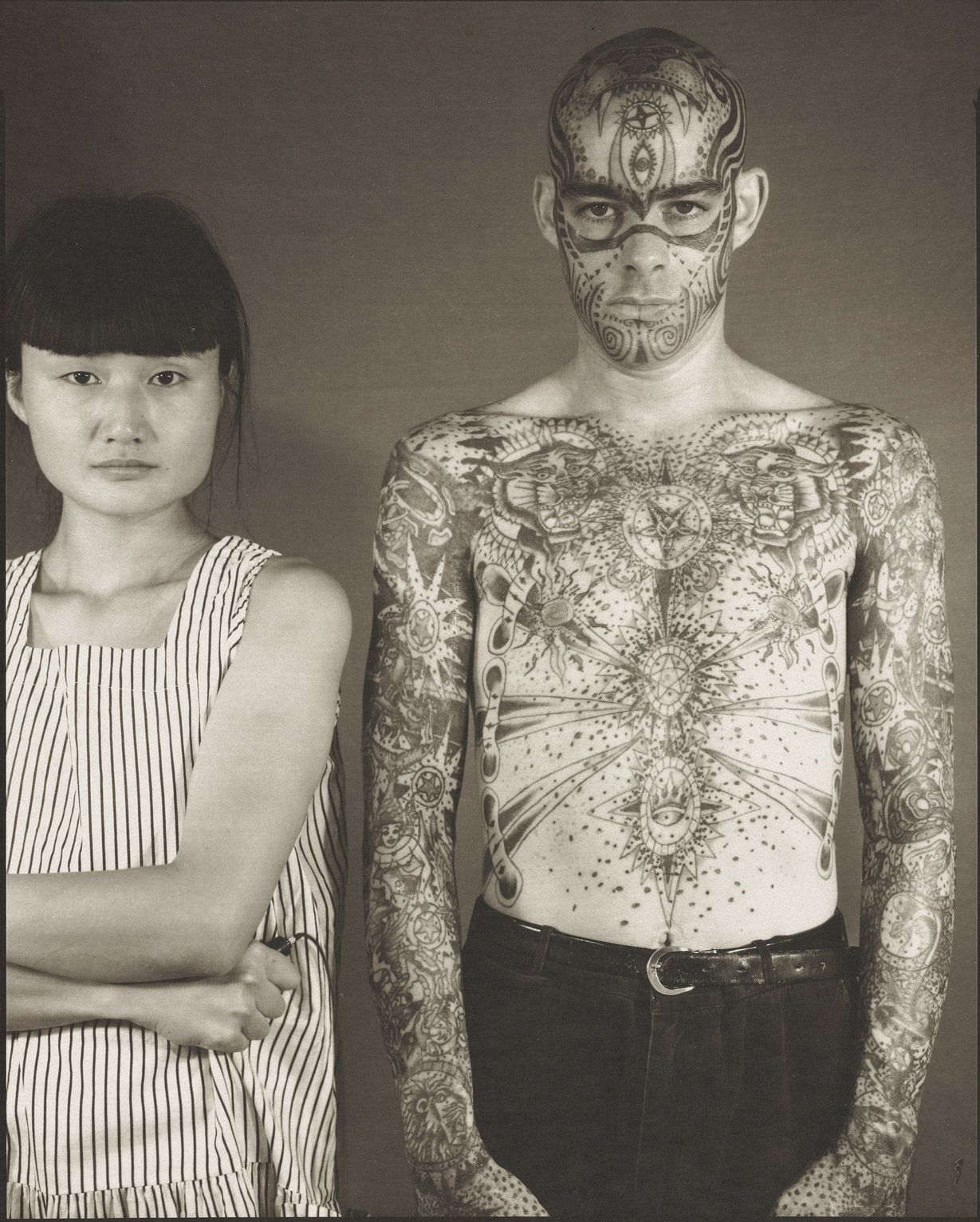 Madoka Takagi with bare-chested, tattooed Latino man