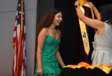 Student receives sash on stage during ceremony.