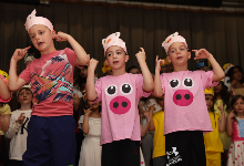 Second graders wearing T-shirts with pig faces on clothing perform.