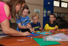 First graders work on art project with assistance from teacher.