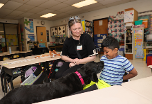 Guide dog is fed by student as handler observes.