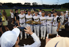 Several players pose with championship trophy as families take photos.